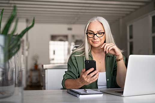 woman with white hair looking at her phone, using a mobile app to request electronic PHI