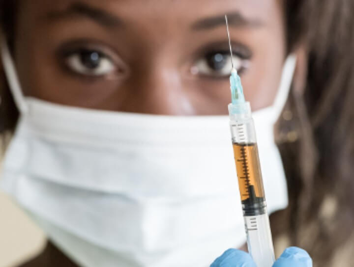 Black woman holding vaccine syringe