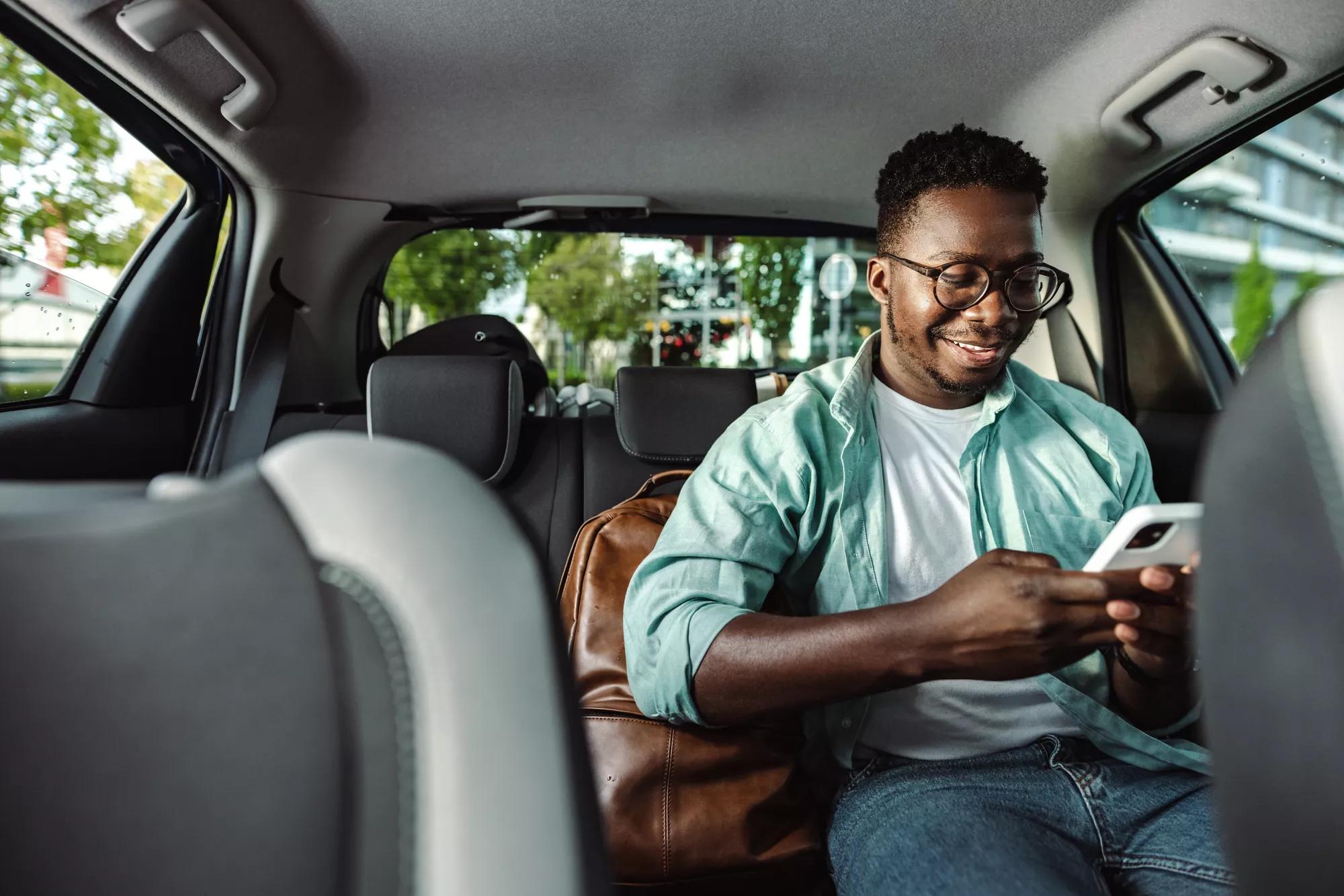 African-American male commuterusing a mobile phone in taxi
